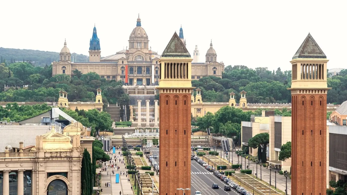 Barcelona, Spanien: Plaza de España mit den Venezianischen Türmen und dem Palau Nacional. Bewölkter Himmel, Verkehr.