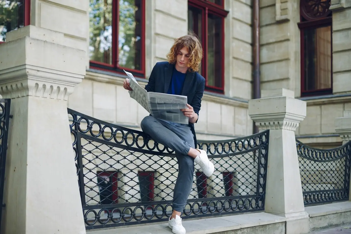 Mann liest Zeitung in der Nähe eines Gebäudes im alten Stil